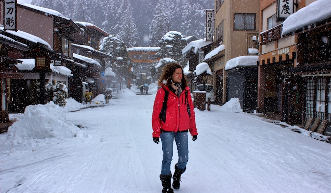 A solo female traveler walking on a snowy road in Japan in winter