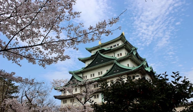 A traditional Japanese castle surrounded by trees and bright blue skies