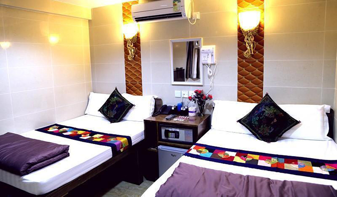 Two double beds with a mini fridge between them in a room at Australia Guesthouse at Chungking Mansions complex in Hong Kong