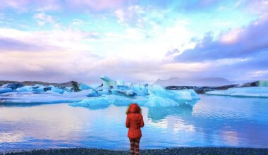 solo female traveler in a read coat at the Glacier Lagoon in Iceland