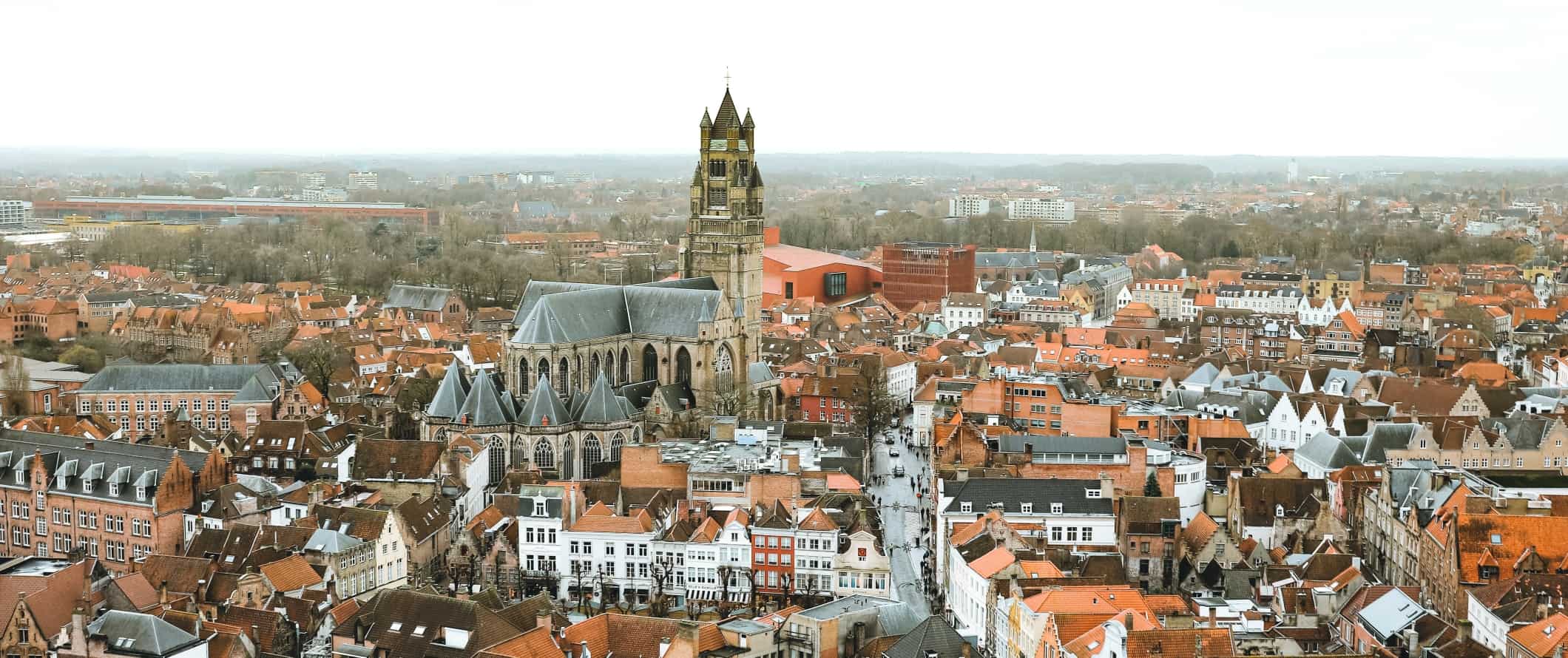 Panoramic view over the red rooftops of the historic center of Bruges with a large stone cathedral in the center, in Belgium