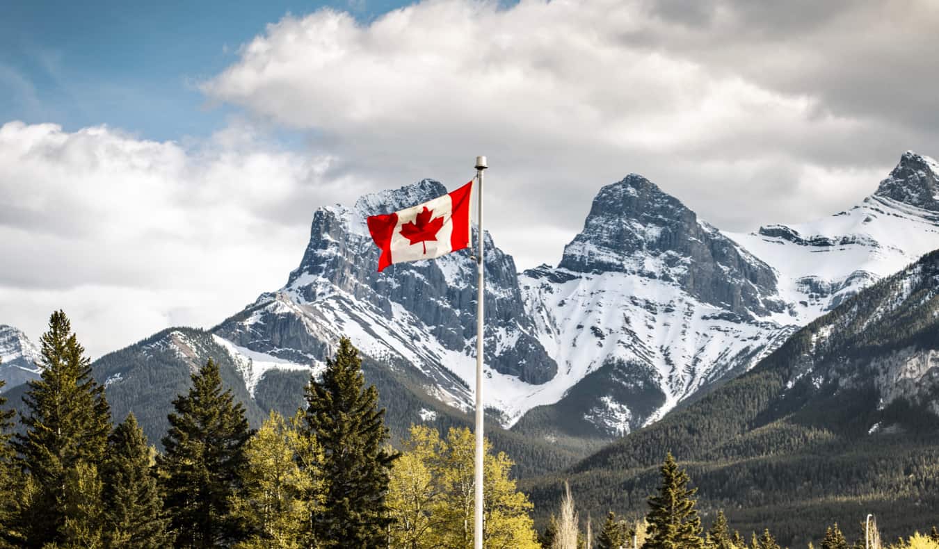 A Canadian flag flying near a snow-capped mountain