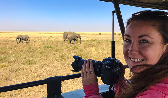 Helen holding a DSLR camera ready to take a photograph of some elephants in the wild