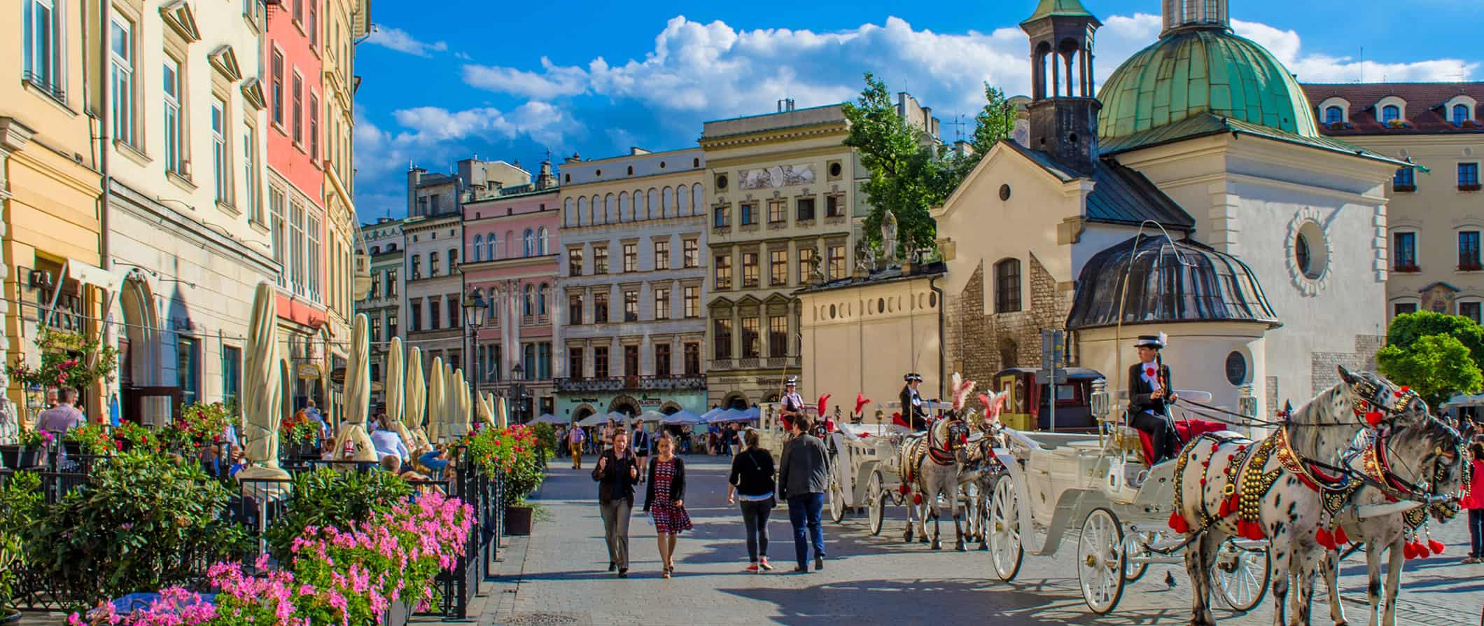 view of Krakow's historical city square with people walking around on a sunny day