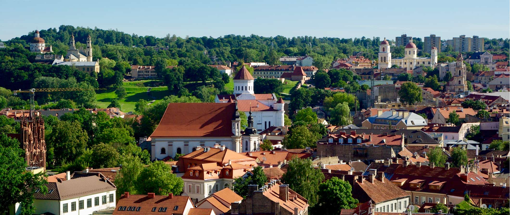Historic buildings surrounded by lush, greens forests in Lithuania on a sunny day