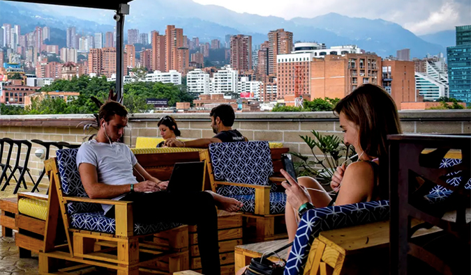 People sitting on outdoor terrace with Medellin skyline in the background at Los Patios hostel in Medellin