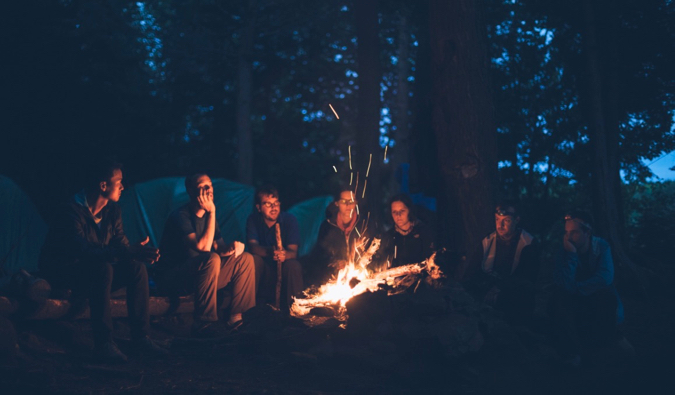 A group of friends and travelers sitting by a fire at night