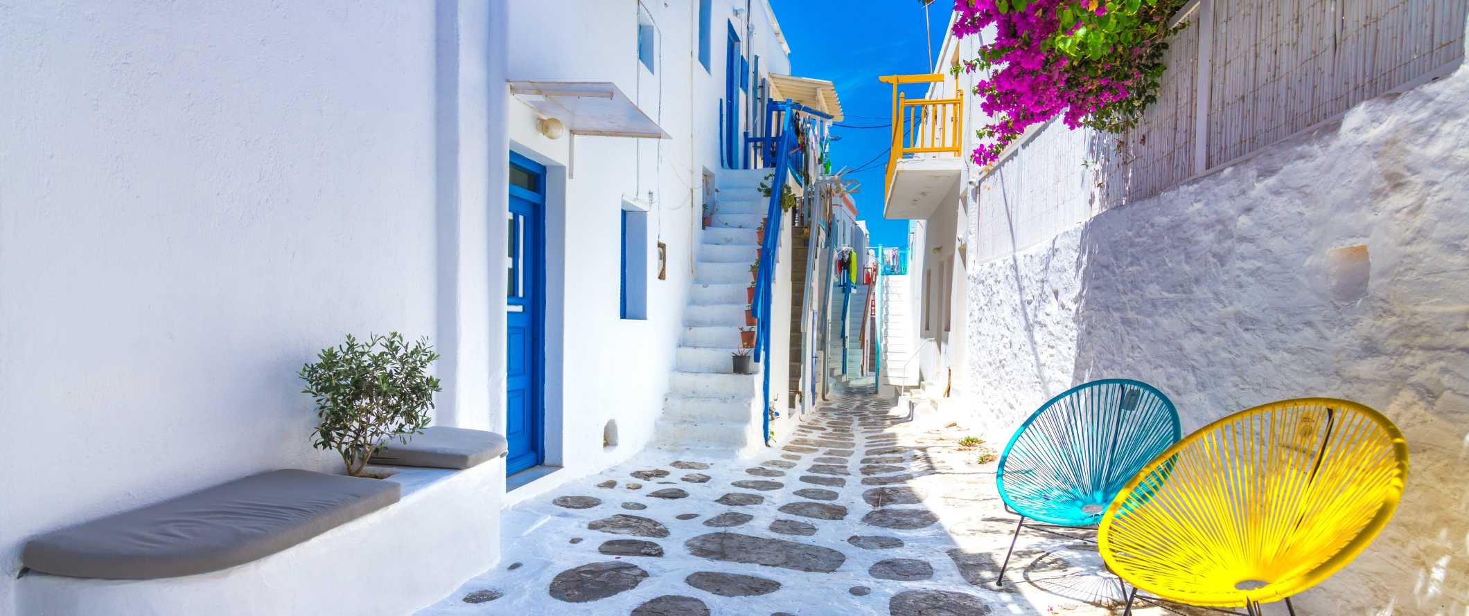 Street in Mykonos old town with white-washed buildings with blue doors and windows on the island of Mykonos in Greece.