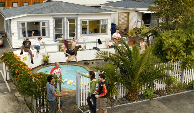 Bungalow hostel with people jumping into a pool in New Zealand