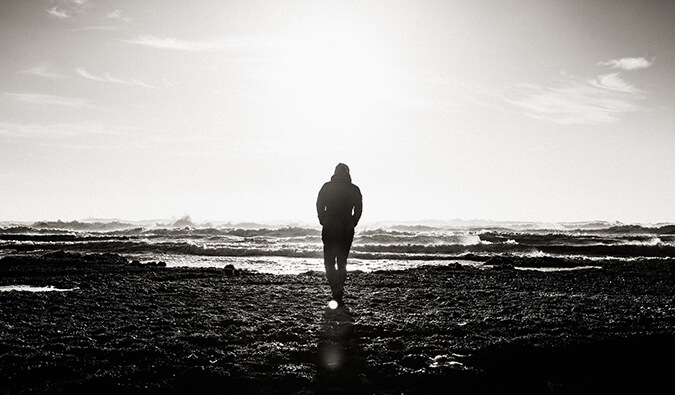 man walking alone on a beach. Image is black and white