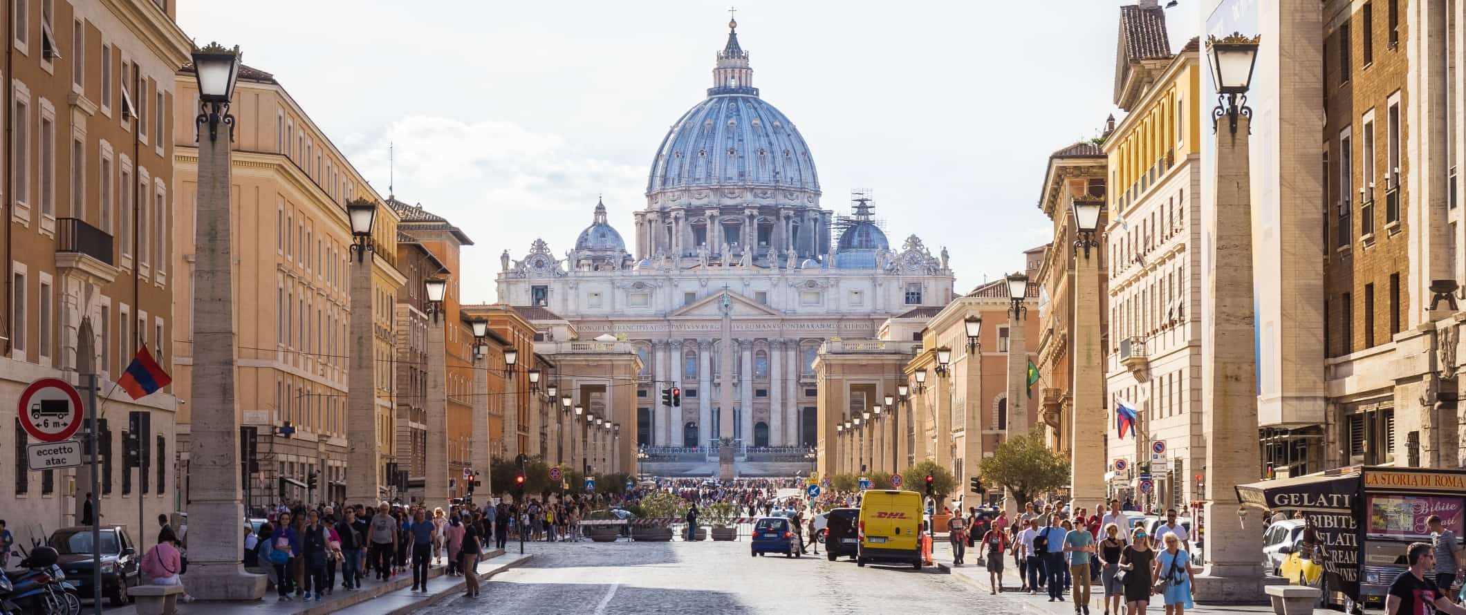 Wide street filled with people and basilica at the end in Rome, Italy