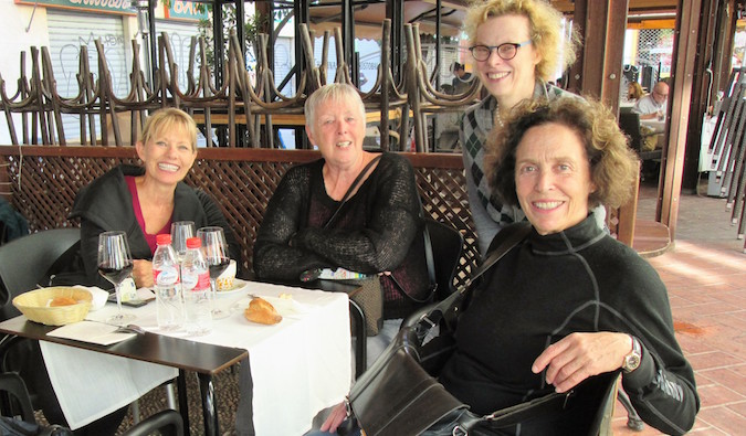 Older female travelers meet up overseas at a restaurant