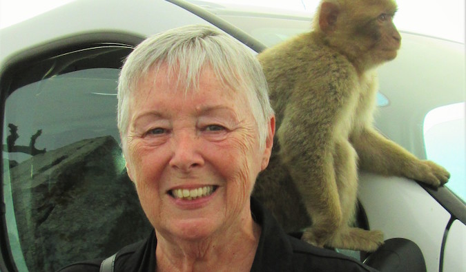 Senior traveler Sherrill with a monkey on her shoulder on a trip overseas
