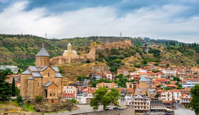 Tbilisi Old Town with historic buildings, churches, and city walls set into the rolling hills behind