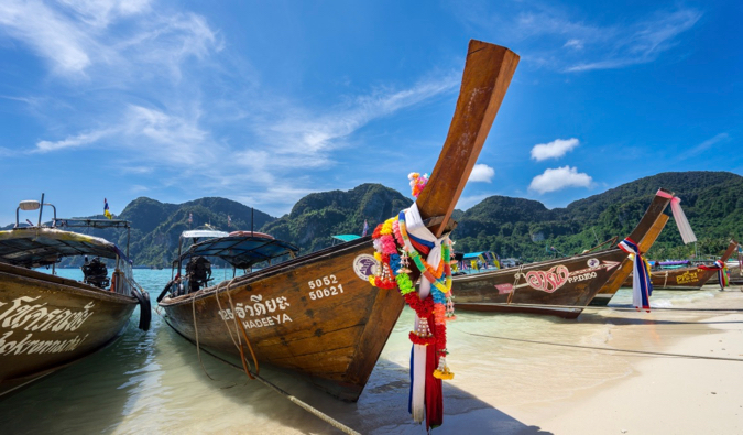 The longtail boats of Koh Phi Phi parked in the sand in front of a bright blue sky in Thailand