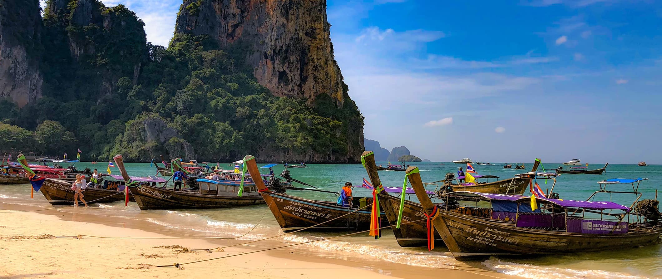 A row of longtail boats parked on a stunning beach in Thailand