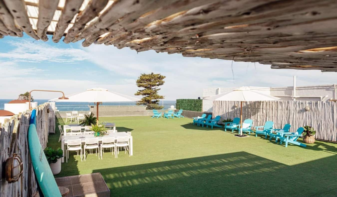 Rooftop with lawn chairs, umbrellas, and tables at wake Up! Bondi Beach hostel