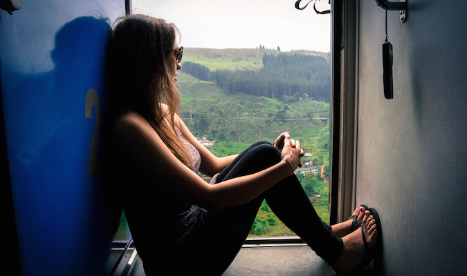 a solo traveler looking across the landscape from a train